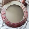 okruglo ogledalo oslikanog rama sa motivom crvenog poljskog cveća koje nalikuje gipsofili